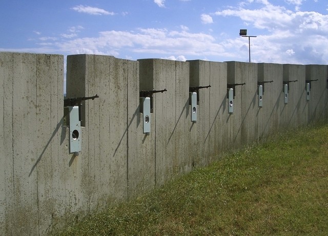 Nel muro sono cementati i mitra dei fucilatori