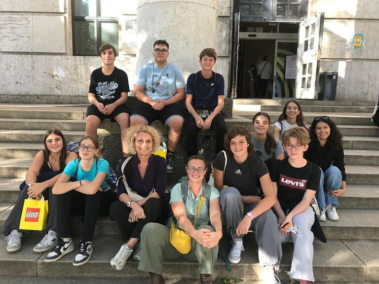 foto di ragazze e ragazzi del gruppo di lettura e accompagnatori in posa sui gradini dell'ingresso della Jugendbibliothek durante la gita a Monaco
