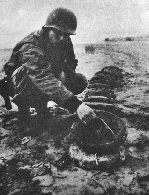 Un soldato americano controlla alcune mine tedesche sulla spiaggia di Cinquale in Toscana 