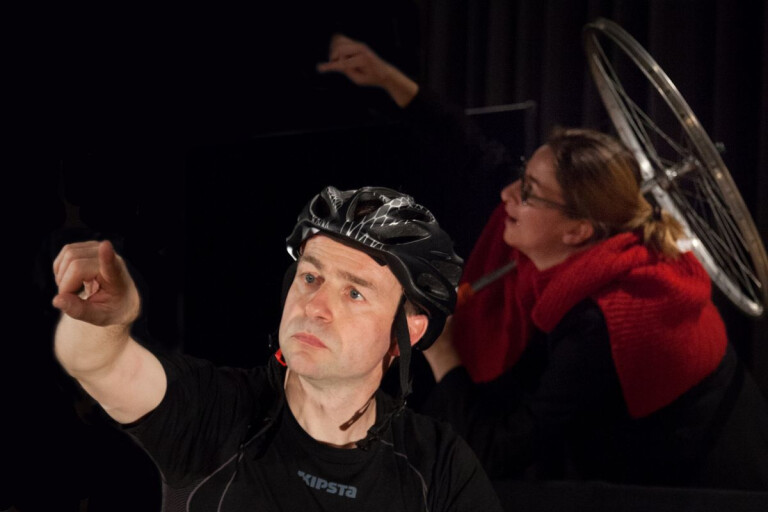 Foto di un uomo con casco da bicicletta che indica un punto lontano, tratto dallo spettacolo teatrale Fiatone – Io e la bicicletta