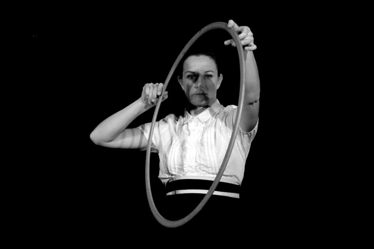 Attrice in scena con un cerchio di bicicletta nello spettacolo teatrale su Alfonsina Strada